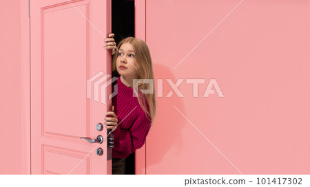 Beautiful, young, blonde teen girl peeking out pink door and looking with attention, Overhearing secrets. Curiosity Beautiful, young, blonde teen girl peeking out pink door and looking with attention, Overhearing secrets. Curiosity 101417302