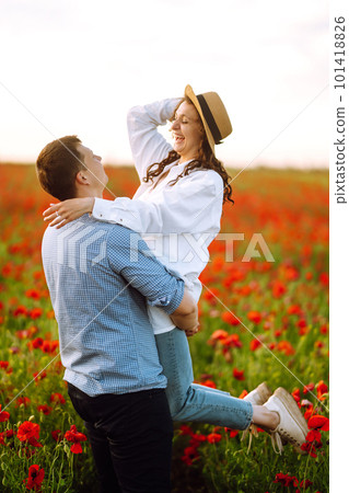 Loving couple walking on the poppy field. Enjoying time together. The concept of youth, love and lifestyle. Loving couple walking on the poppy field. Enjoying time together. The concept of youth, love and lifestyle. 101418826