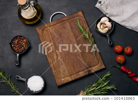 Empty brown wooden board and spices on black table, top view Empty brown wooden board and spices on black table, top view 101418863
