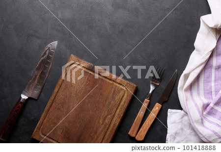 Empty wooden kitchen cutting board, knife and fork with wooden handle on black background, top view 101418888