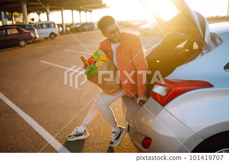 Young man with shopping bag full of vegetables near the car. Healthy lifestyle. 101419707