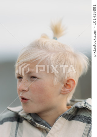 Close up of a blonde boy face with cute hairstyle with tail on top, explaining something, boy seriously talking to his friend Close up of a blonde boy face with cute hairstyle with tail on top, explaining something, boy seriously talking to his friend 101419891