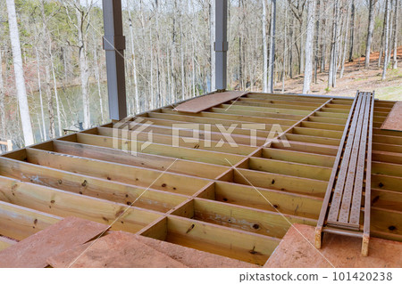 An newly constructed layout of flooring joists inside new custom built home with wooden deck patio 101420238