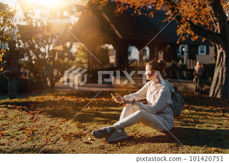 Young Fashionable Teenage Girl With Smartphone In Europian Park In Autumn Sitting At Smiling. Trendy Young Woman In Fall In Park Texting. Retouched, Vibrant Colors. Beautiful Blonde Teenage Girl Young Fashionable Teenage Girl With Smartphone In Europian Park In Autumn Sitting At Smiling. Trendy Young Woman In Fall In Park Texting. Retouched, Vibrant Colors. Beautiful Blonde Teenage Girl 101420751