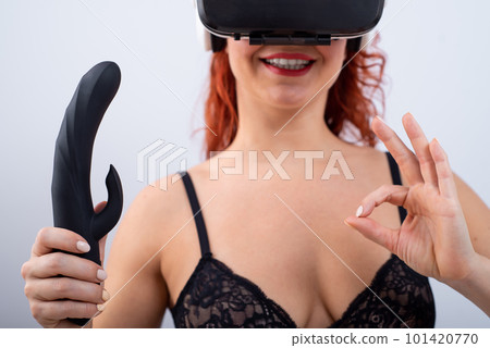 Woman in virtual reality glasses holding black dildo on white background. Woman in virtual reality glasses holding black dildo on white background. 101420770