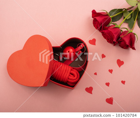 Bdsm set in a box in the form of a heart and red roses on a pink background. Valentine's day gift idea 101420784