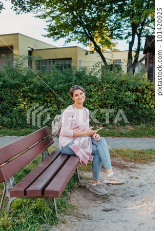 Girl enjoying city view from a bench in sunset or sunrise time. Beautiful blond-haired pretty girl in summer green park against sunset beams. Lonely woman sitting alone moments sunset. On Blurred Girl enjoying city view from a bench in sunset or sunrise time. Beautiful blond-haired pretty girl in summer green park against sunset beams. Lonely woman sitting alone moments sunset. On Blurred 101420925