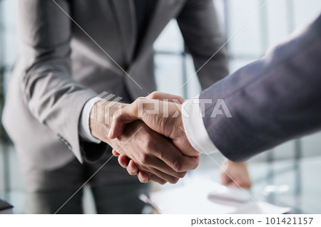 Handshake of two businessmen who enters into the contract to develop a new software to improve business service at a company. Handshake of two businessmen who enters into the contract to develop a new software to improve business service at a company. 101421157