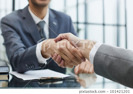 Portrait of confident mature specialist sitting at the table and reaching out his hand to the camera for a handshake Portrait of confident mature specialist sitting at the table and reaching out his hand to the camera for a handshake 101421201