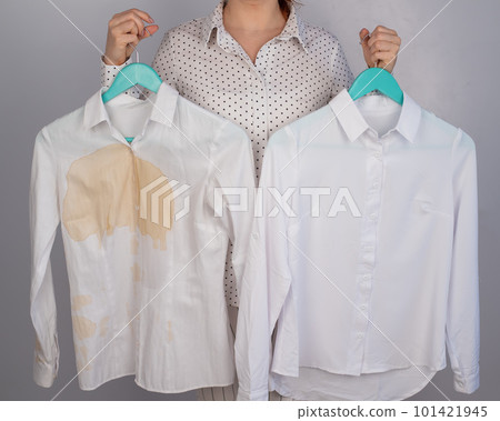 A woman compares two white shirts before and after washing. The girl is holding one blouse, clean and ironed, and the other, dirty with coffee stains 101421945
