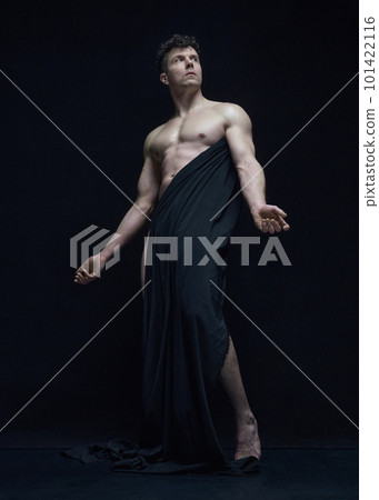 Full-length portrait of mature, handsome, shirtless man posing in dark fabric against black studio background Full-length portrait of mature, handsome, shirtless man posing in dark fabric against black studio background 101422116