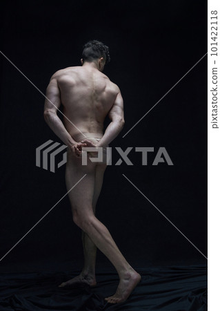 Full-length portrait of handsome shirtless muscular man posing in underwear against black studio background. Back view 101422118