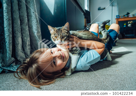 Portrait of a Happy smiling kid at home playing with a kitty cat. Caucasian boy lying on a carpeted floor holding his cat in the living room. Life with a pet. Best friends.Selective focus. Portrait of a Happy smiling kid at home playing with a kitty cat. Caucasian boy lying on a carpeted floor holding his cat in the living room. Life with a pet. Best friends.Selective focus. 101422234