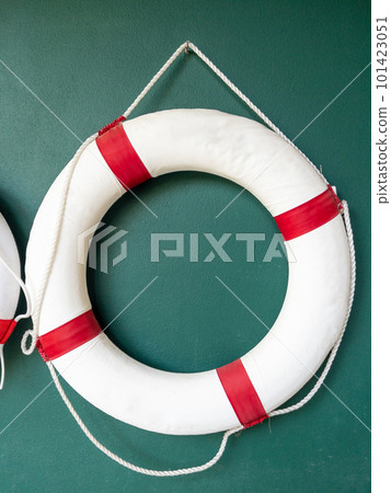 Closeup of the white lifebuoy is hanging on the green wall. 101423051
