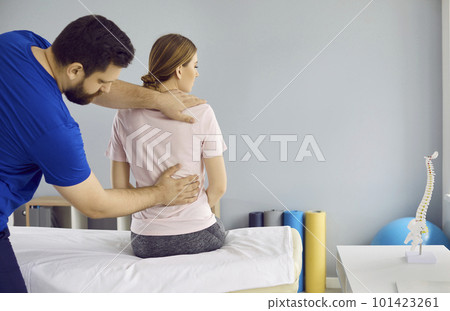 Professional physiotherapist treats young woman's spine pain in modern medical clinic. 101423261