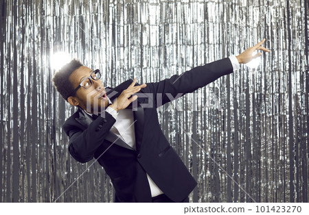 Happy funny young ethnic guy in trendy tuxedo dab dancing and having fun at party 101423270