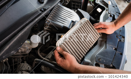An auto mechanic is changing the air filter in the car An auto mechanic is changing the air filter in the car 101424340