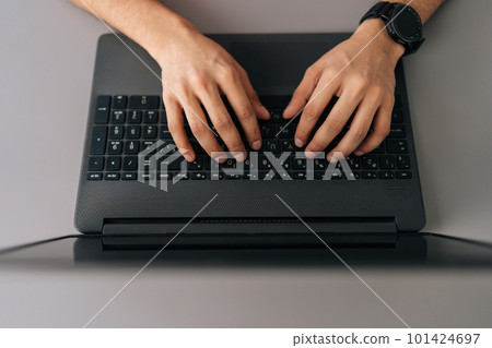 Close-up top view of unrecognizable businessman wearing smartwatch typing on laptop computer sitting at desk in office. Close up cropped shot of freelancer male working on laptop at home office room. Close-up top view of unrecognizable businessman wearing smartwatch typing on laptop computer sitting at desk in office. Close up cropped shot of freelancer male working on laptop at home office room. 101424697