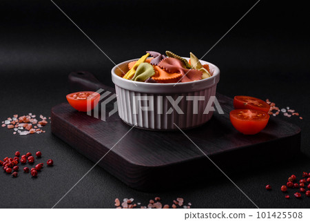 Raw farfalle pasta in different colors on a dark concrete background 101425508