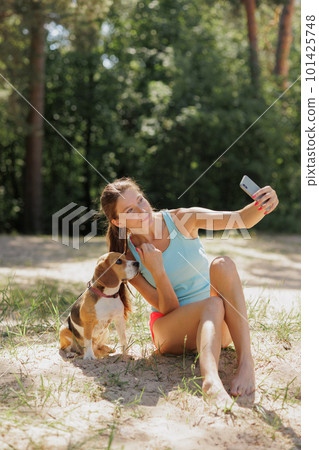 taking selfies, portrait of Caucasian woman and beagle dog in nature in park. cute pet having fun on vacation 101425748