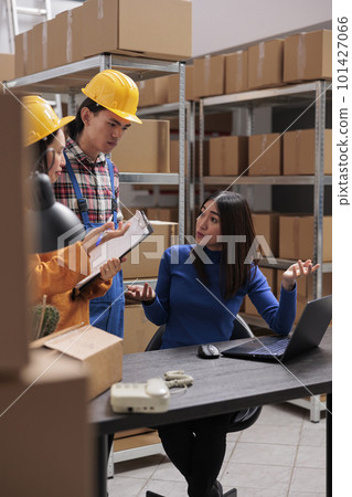 Warehouse workers listening to logistics manager instructions and taking notes on clipboard. Asian storehouse employees team cooperating to pick order and prepare parcel for shipment 101427066