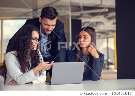 Business team collaborating on project together, using laptops. Business colleagues in casual working together in contemporary office space. 101431615