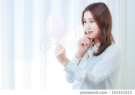 微笑的年輕女子,手托著下巴,看著手鏡 微笑的年輕女子,手托著下巴,看著手鏡 101431813