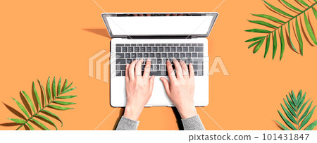 Person using a laptop computer with tropical leaves 101431847