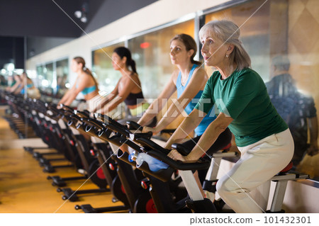 Mature woman taking cycling class at gym 101432301