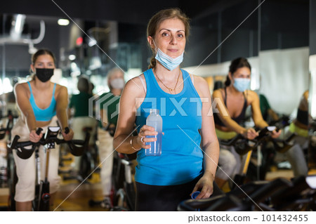 Woman drinking water during workout in gym Woman drinking water during workout in gym 101432455