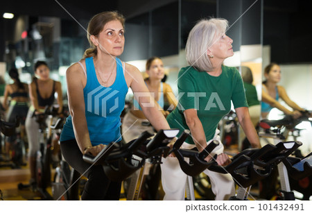 Two mature woman training on fitness bikes Two mature woman training on fitness bikes 101432491
