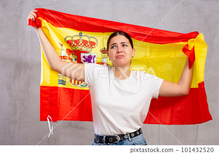 Sad young woman holding Spain flag against unicoloured background 101432520