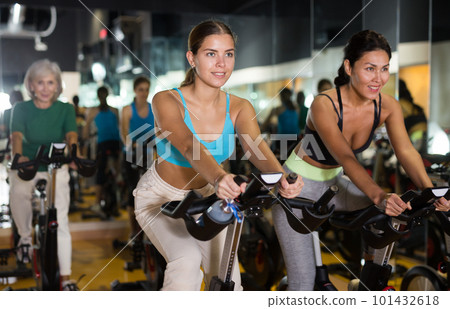 Women training on stationary bikes at gym 101432618