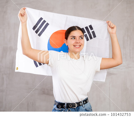 Joyous young woman holding South Korea flag against unicoloured background 101432753