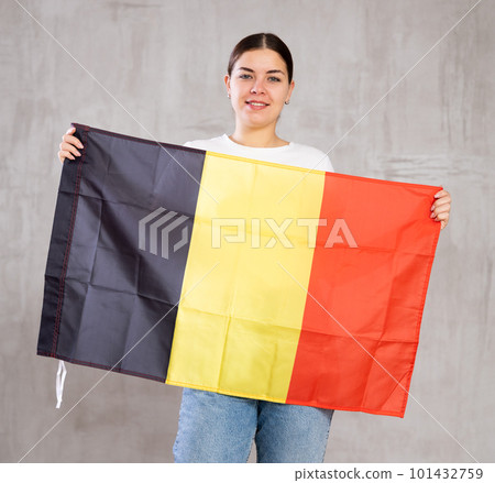 Joyous young woman holding Belgium flag against unicoloured background Joyous young woman holding Belgium flag against unicoloured background 101432759