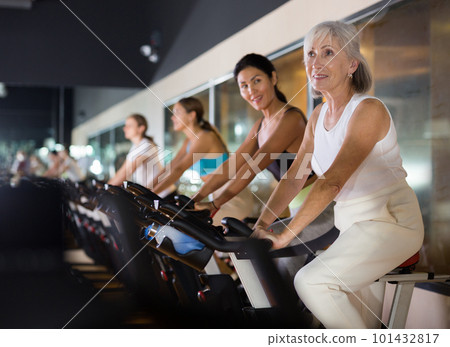 Mature woman taking cycling class at gym 101432817
