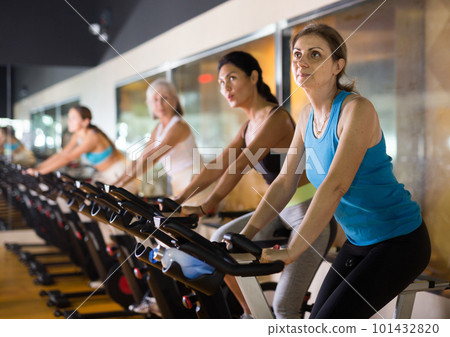 Woman riding stationary bike at fitness center 101432820