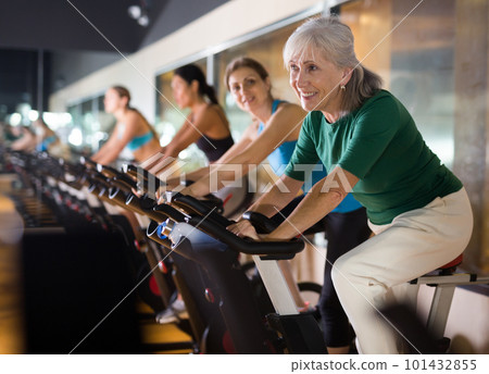 Mature woman taking cycling class at gym 101432855