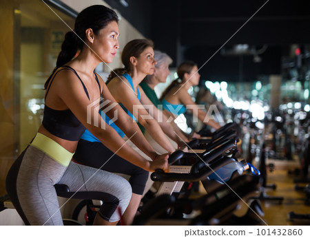 Woman on stationary bike workout in gym 101432860