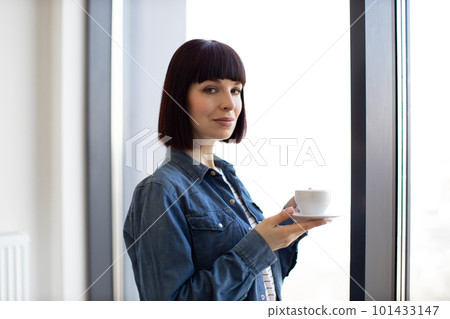 Woman with coffee cup enjoying view from panoramic window 101433147