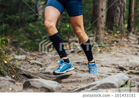 legs runner in compression sleeves on his feet run forest trail race over stones, summer marathon race legs runner in compression sleeves on his feet run forest trail race over stones, summer marathon race 101433181
