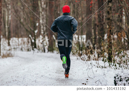 back male runner running trail marathon, man jogging snowy forest in winter clothes, cold weather back male runner running trail marathon, man jogging snowy forest in winter clothes, cold weather 101433192