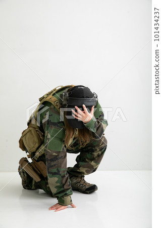 A woman wearing camouflage clothes and holding her head 101434237