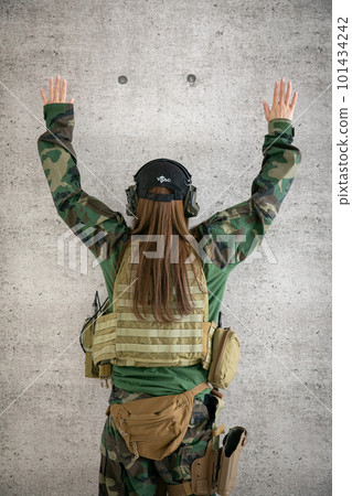 A woman wearing camouflage clothing and raising her hands camouflage 101434242