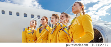 Joyful stewardesses standing near aircraft at airport Joyful stewardesses standing near aircraft at airport 101435517
