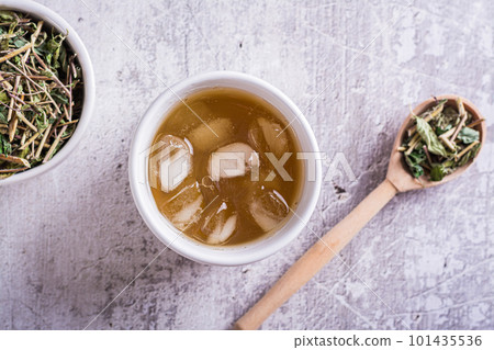 Close up of cold green Japanese hojicha tea with ice in cups and dry tea in a bowl top view 101435536