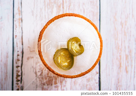 Close up of spicy cocktail with margarita, egg foam, tagine and jalapeno peppers in glasses top view 101435555