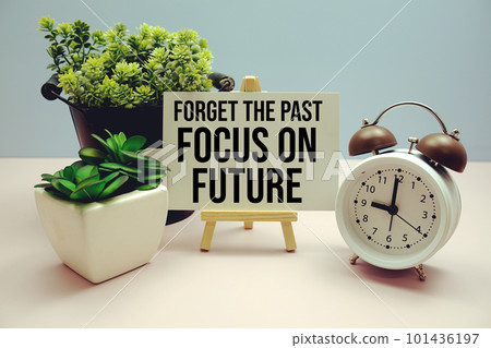"Forget The Past Focus on Future" Inspirational and motivational quote written on paper card with alarm clock on blue background "Forget The Past Focus on Future" Inspirational and motivational quote written on paper card with alarm clock on blue background 101436197