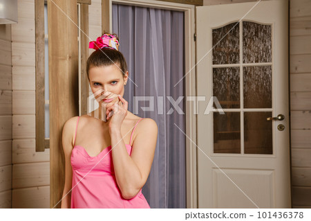 Playful adult woman leaning to the porch of wooden cabin 101436378