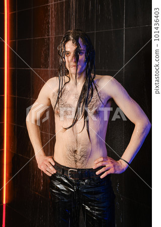 Handsome man with long hair and wet torso on a dark background in shower 101436403